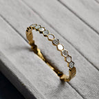 Gold bracelet with hexagonal links featuring mother-of-pearl and crystal accents on textured surface