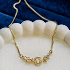 Gold necklace with a decorative clasp on a white stand against a blue fabric background