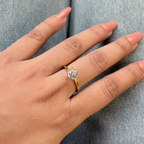 Hand wearing a gold ring with a diamond on a denim background