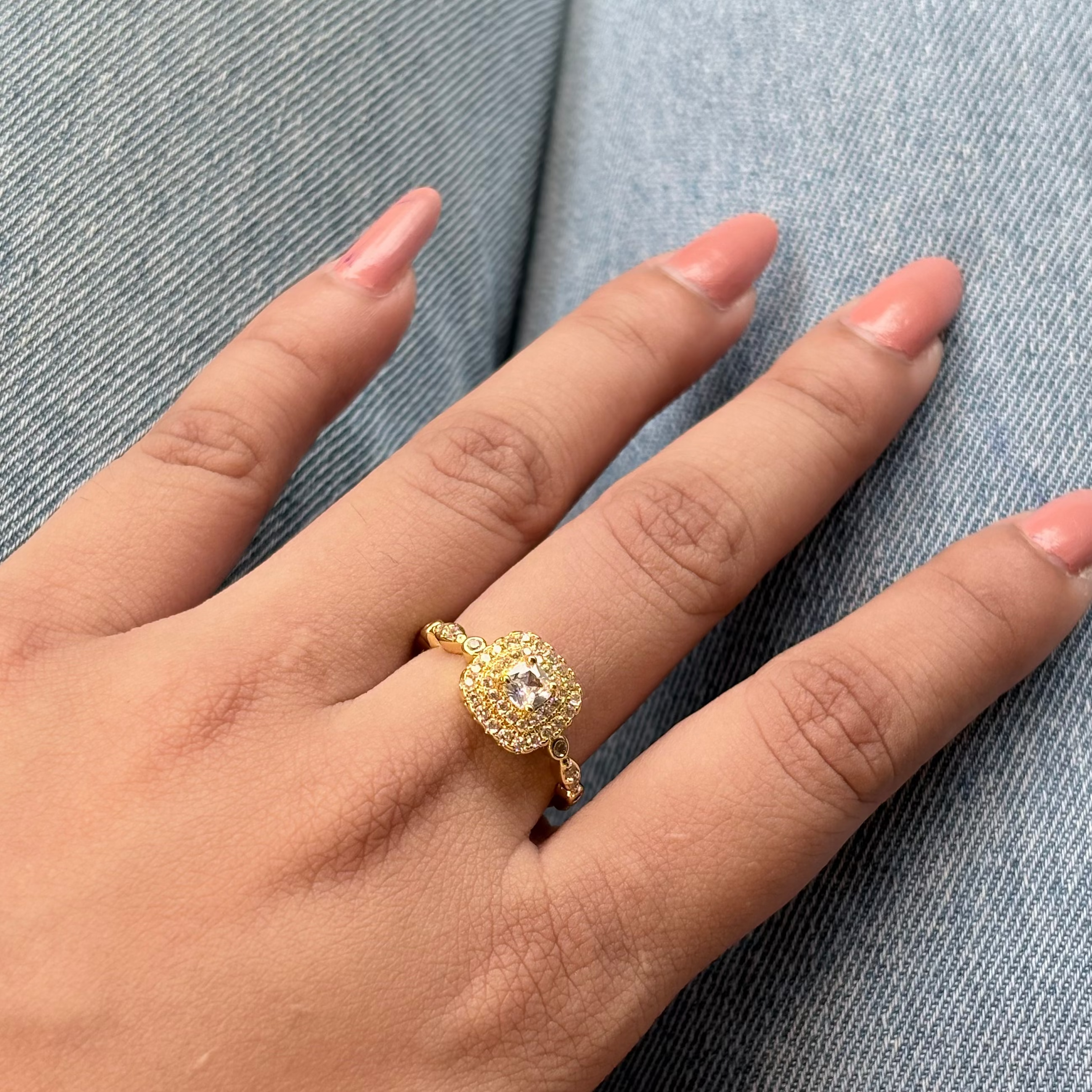 Gold ring on a hand with a blue denim background