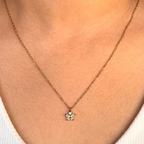 Necklace with a small pendant worn by a person, close-up of the necklace on skin.