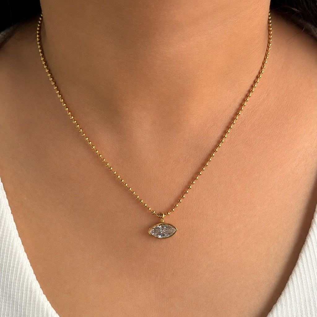 Gold necklace with a pendant on a person wearing a white top