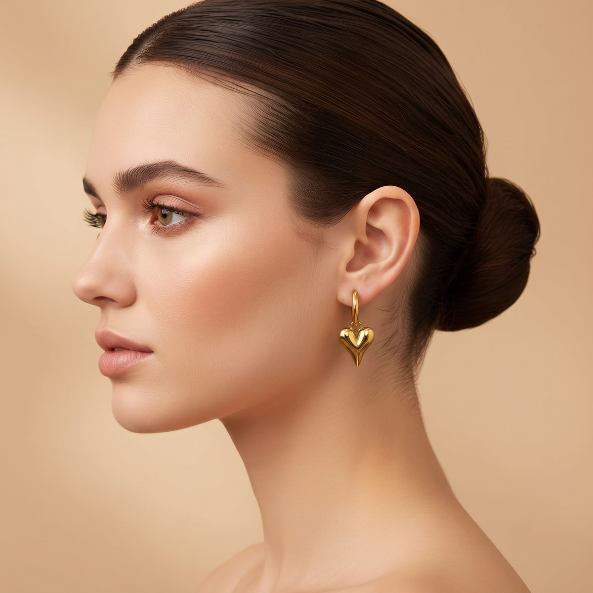 Lena Puff Heart Huggie Earrings in 18K gold PVD-plated finish worn on the ear