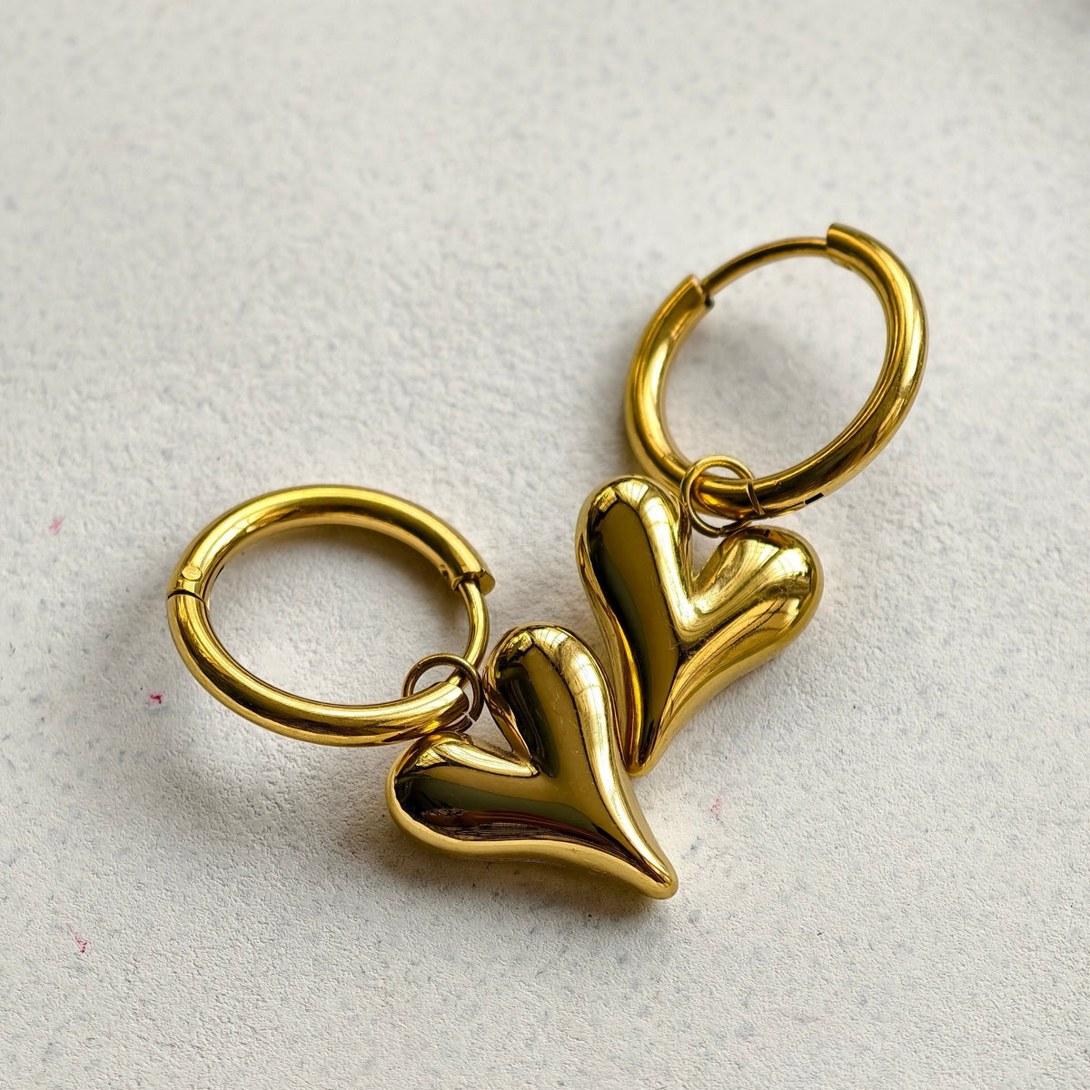 Lena Puff Heart Huggie Earrings, close-up on a display