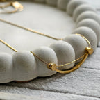 Smiley Curve Minimal Necklace, close-up on a display