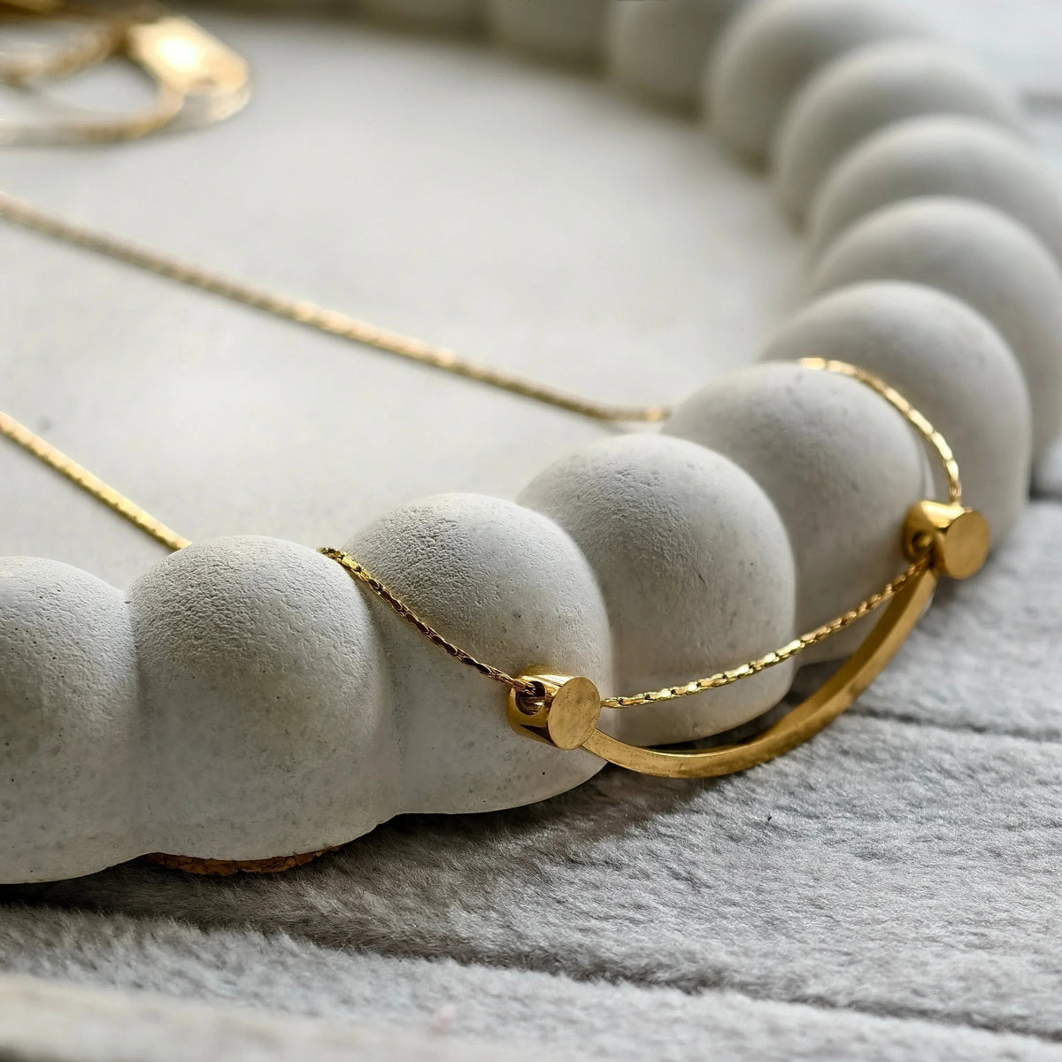 Smiley Curve Minimal Necklace, close-up on a display
