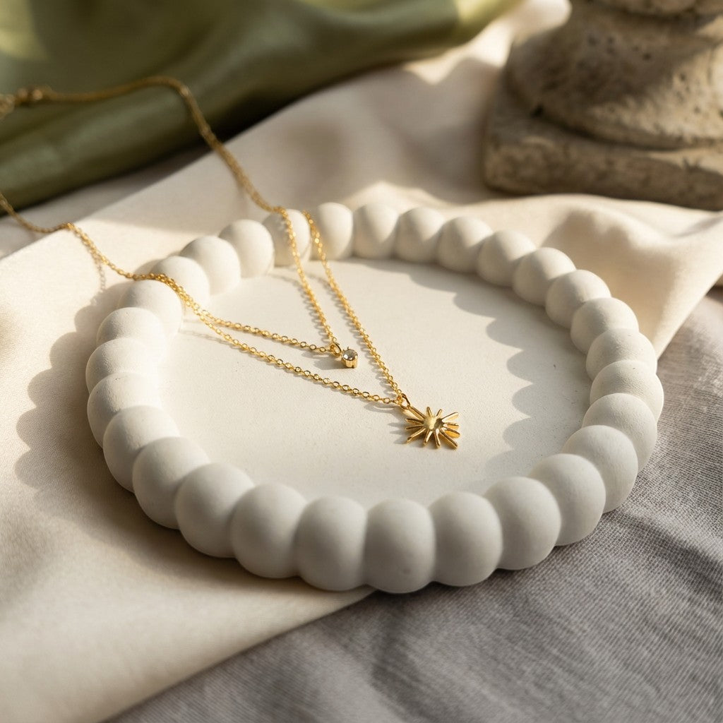 Pretty Shimmering Things Global gold layered necklace with a zircon charm and star pendant on a white textured tray.