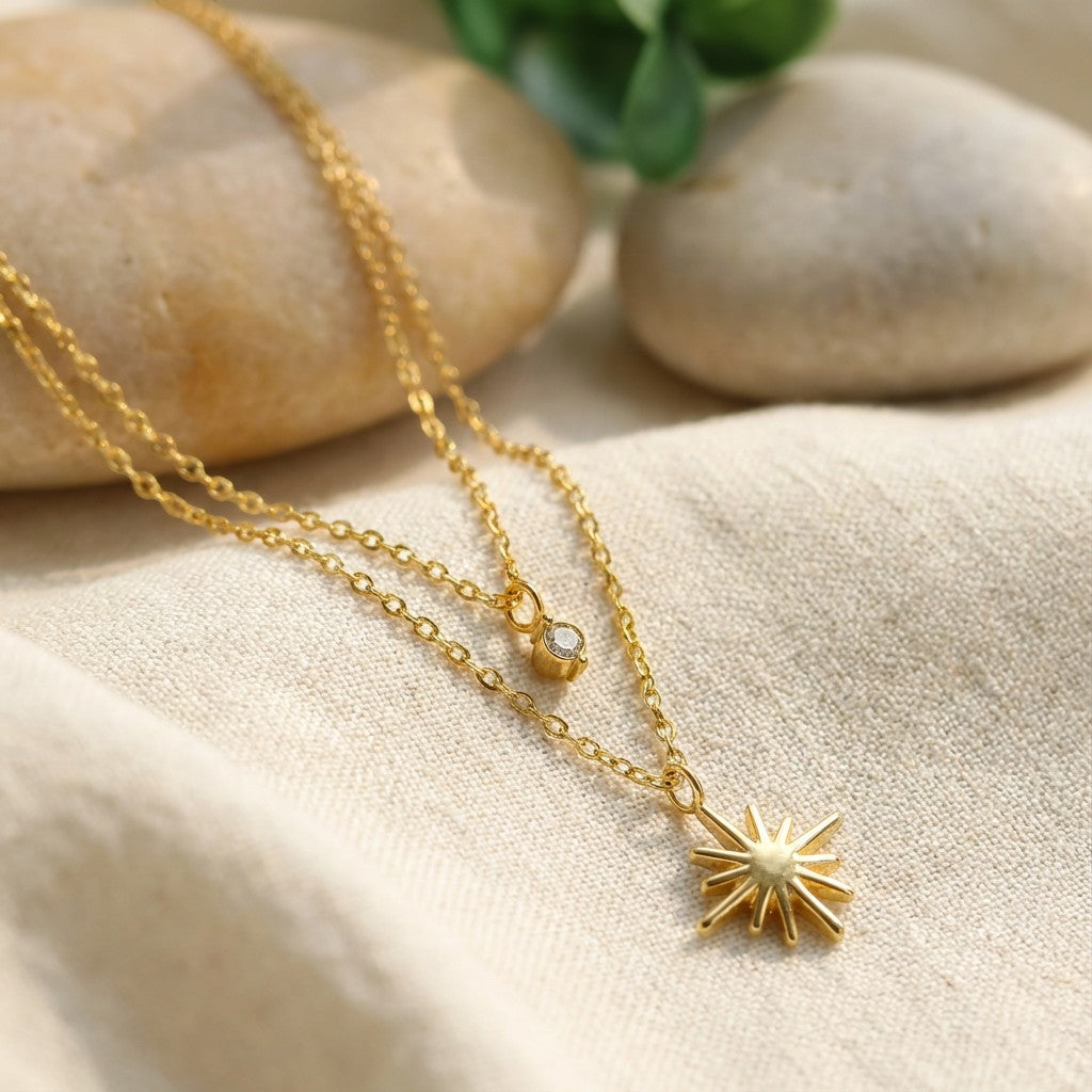 Pretty Shimmering Things Global gold layered necklace with a zircon charm and a radiant star pendant on a soft cloth.