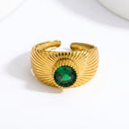 Pretty Shimmering Things gold-tone sunburst statement ring with a deep emerald-green gemstone and adjustable open band.