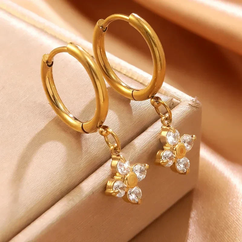 Pretty Shimmering Things gold hoop earrings with dangling flower charms featuring sparkling clear cubic zirconia stones.