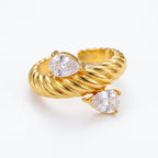 Pretty Shimmering Things gold-tone twisted rope bypass ring with two pear-cut cubic zirconia stones on a white background.